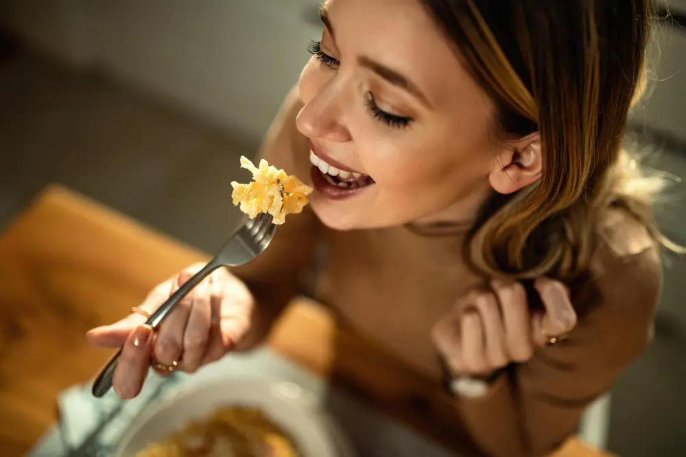 imagem de uma mulher jovem almoçando feliz com seus bons habitos alimentares